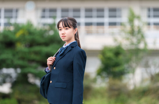 学校の校舎の前に立つ制服姿の中学生・高校生・小学生
