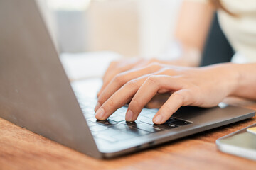 Hands typing on a laptop keyboard in a well-lit workspace, ideal for business, education, or remote...