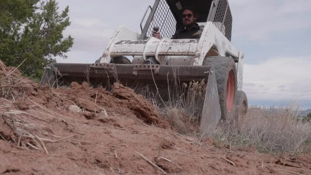 Skid Steer Scooping Dirt with Front End Loader