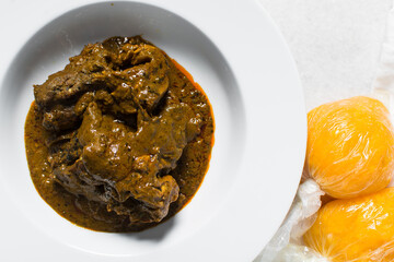 Overhead view of Nigerian banga soup with fish and beef in a white plate, top view of palm nut soup...
