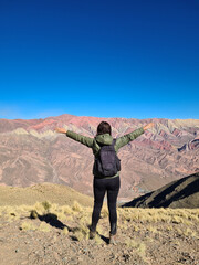 Fototapeta premium Woman with backpack looking at colorful mountains