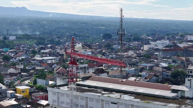 Indonesia city with construction site and crane, aerial orbit view