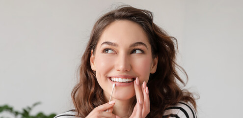 Young woman with cotton bud at home