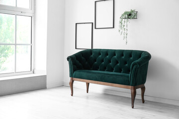 Stylish green sofa near white wall in living room