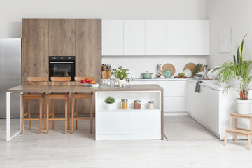 Interior of modern kitchen with island table and white counters