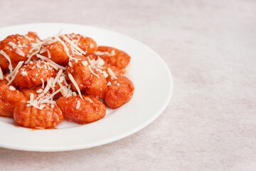 Plate of tasty gnocchi with cheese on white background