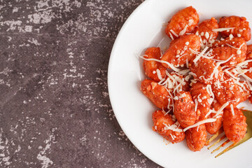 Plate of tasty gnocchi with cheese on grey background