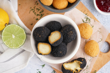 Bowls with different delicious fried mozzarella balls and lime on light background, closeup