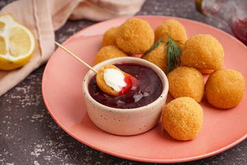Plate with delicious fried mozzarella balls and sweet sauce on grunge background, closeup