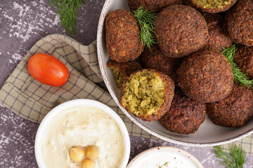 Bowl with delicious falafel balls, hummus and tomato on grunge background, closeup