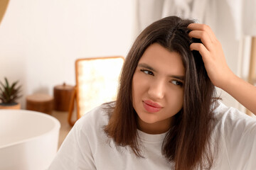 Stressed young woman with dandruff problem in light bathroom