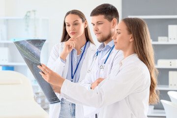 Young doctors studying x-ray image of spine at hospital