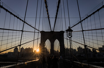 Obraz premium brooklyn bridge at sunrise (new york city landmark over east river to manhattan) travel tourism famous destination in usa america united states (suspension cables lamp light streetlight) people cross