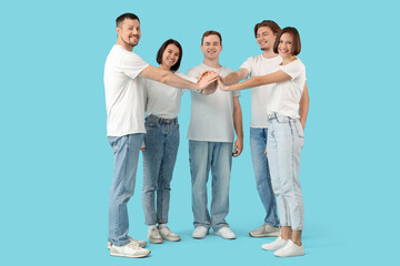 Fototapeta premium Group of young people in jeans putting hands together on blue background