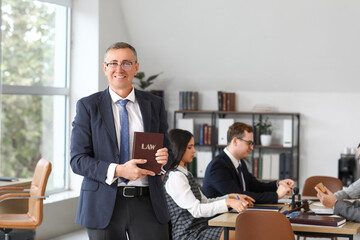 Mature male lawyer with law book working in office