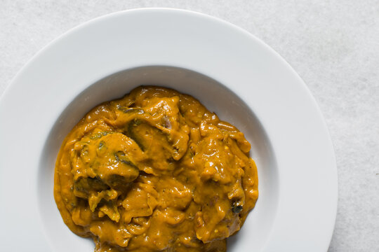 Overhead view of Nigerian owo soup with fish and beef in a white plate, top view of oghwo soup in a large dinner plate, traditional owo soup in a white dish