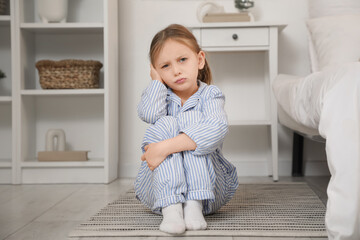 Little girl suffering from ear pain in bedroom