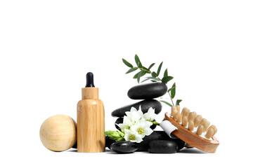 Composition with bottle of serum, spa stones, massage brush and flower on white background