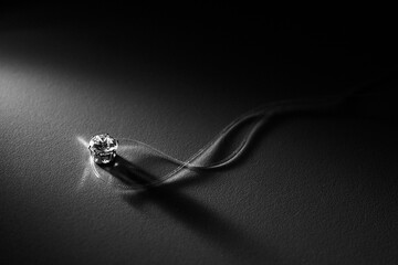 A close-up shot of a diamond pendant on a delicate string, illuminated on a dark background. Ideal for showcasing luxury, elegance, jewelry advertising, and minimalist design concepts.