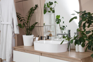 Fototapeta premium Sink with plants and mirror on drawers in bathroom
