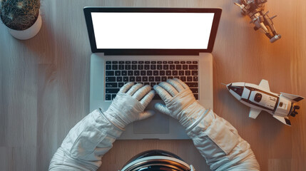Laptop mockup, top view. An astronaut's workplace. Cosmonautics Day is April 12. A man in a space suit is typing on a laptop. There is a rocket model on the table next to the laptop