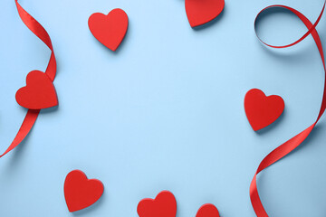 Frame made of ribbon with red hearts on blue background. Valentine's Day celebration
