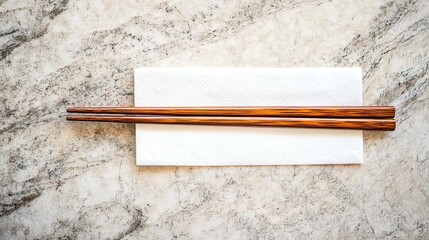 Wooden chopsticks resting on a white napkin on a marble surface.