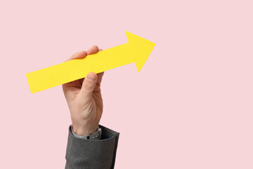 Businessman's hand with arrow pointing at something on pink background
