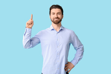Fototapeta premium Young man pointing up on blue background