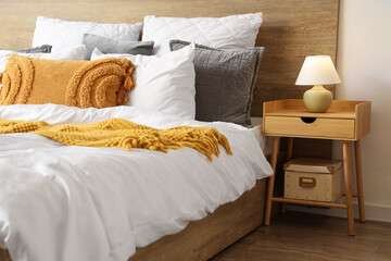 Interior of stylish bedroom with cozy bed and lamp on bedside table