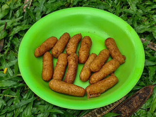 Fried tempura in a green plastic plate on the grass.