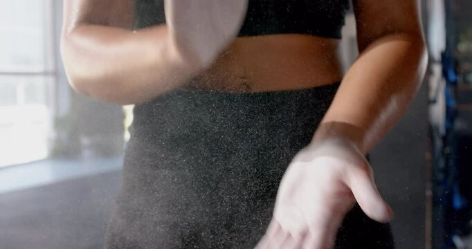 Clapping hands with chalk dust, woman preparing for workout in gym