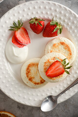 Cottage cheese pancakes (syrniki) with strawberries and sour cream. Healthy breakfast concept.