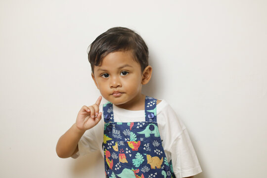 Portrait of smiling young Asian boy holding and showing number one cutout in isolated studio white background for education concept