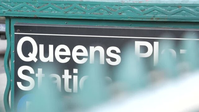 New York subway sign, Queens underground metro station. Metropolitan entrance fence, public transport exit. Long Island city street, NYC United States. Navigation text on signboard. Passenger guidance