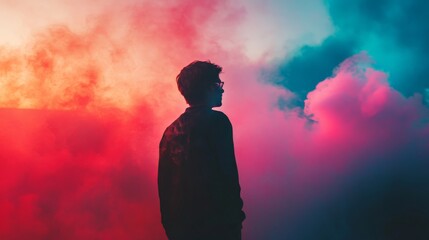 Obraz premium Silhouette of a man standing in front of a vibrant colorful smoke background.