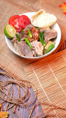 Beef rib soup or Iga soup with clear broth with beef, potato, fresh tomato, lime, green chilies, fried onions, and crackers. Served in a white bowl with unique decoration. Space for text available
