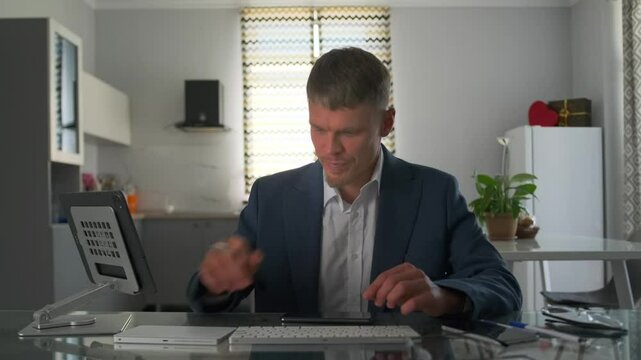 In apartment, the remote worker struggles with a frozen screen, pressing the keyboard and touchpad. He appears confused, trying to identify the system error or figure out what went wrong.