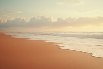 Obraz premium Waves crash along a sandy beach under a cloudy sky.