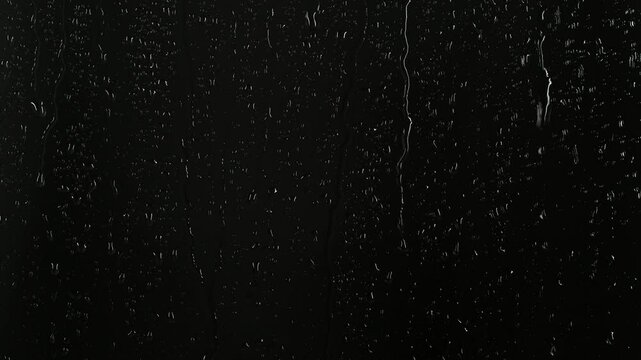 Closeup water rainfall, rain drops falling on window glass over black background