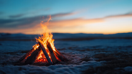 Fototapeta premium Burning campfire surrounded by snow under colorful sunset sky. Outdoor and travel themes