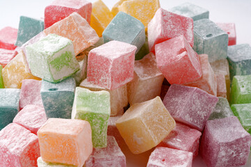 Colorful assortment of traditional Turkish delight cubes arranged in a casual pile on a white surface