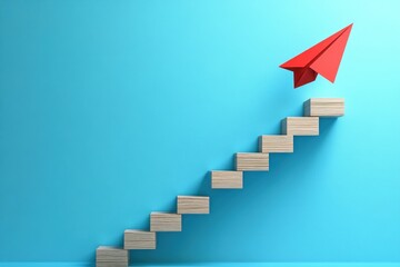Obraz premium Red Paper Airplane Rising on Wooden Block Staircase Against Soft Blue Background, Symbol of Business Growth and Success, Minimalist Design Concept