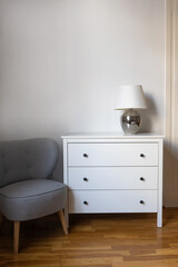 Minimalist interior with white dresser and gray chair