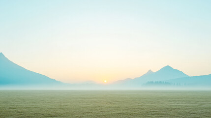 Sunrise over misty mountains and fields in a tranquil landscape