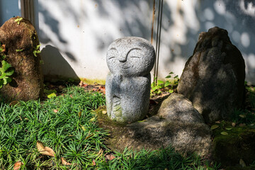 Obraz premium Smiling Jizo Buddha statue on Japanese garden with light shade