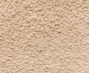 A wall with a tan color and a rough texture