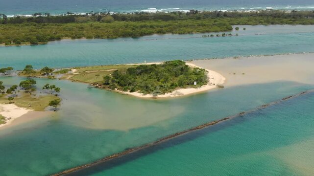 Aerial view of lush green islet surrounded by sandy shores and turquoise waters along Bellinger River, ocean in background, Urunga, New South Wales, Australia