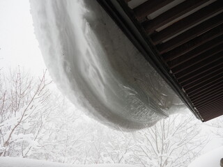 屋根にぶら下がる雪
