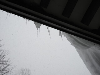 屋根にぶら下がる雪